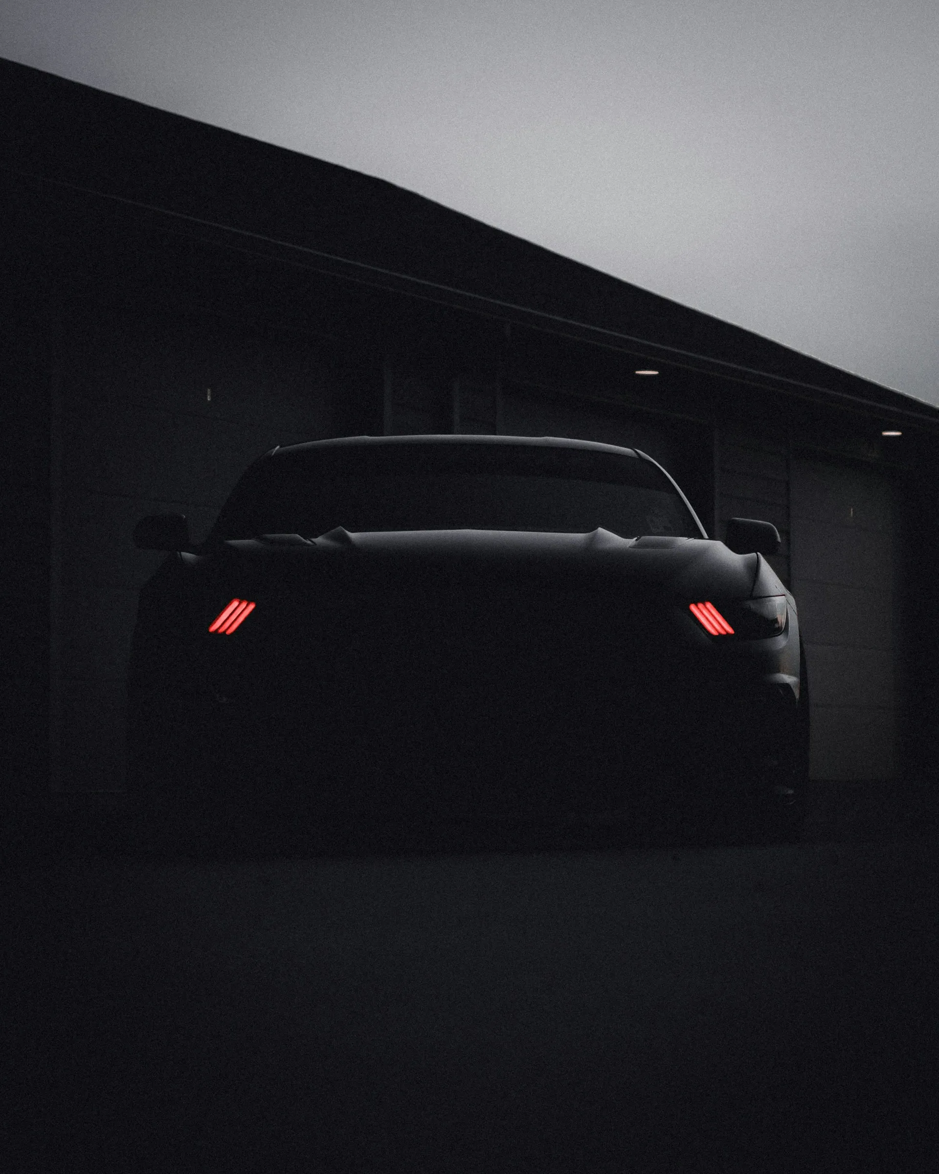Silhouette of a car with glowing red headlights
